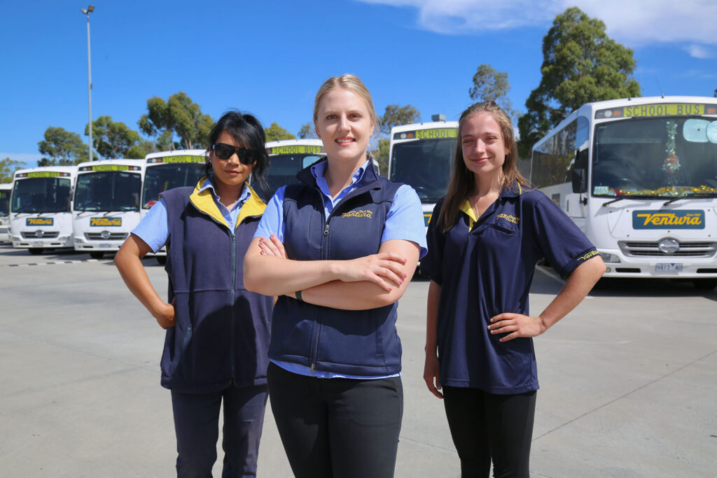 Three women in Ventura uniforms in front of buses