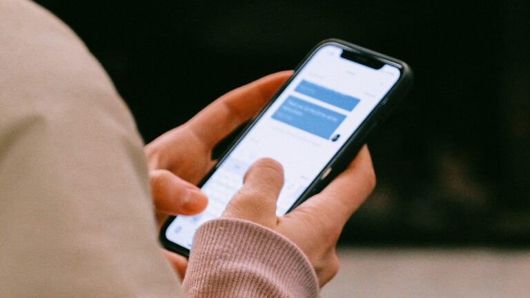 A person holding a mobile phone and typing a message