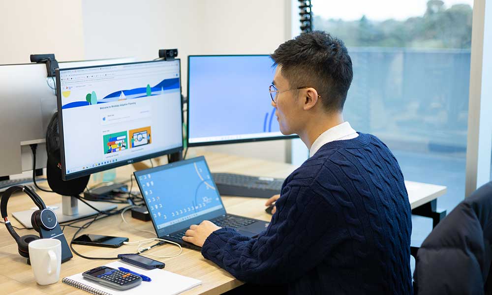 Ted Ma, QMetrix consultant, working at the computer in the office