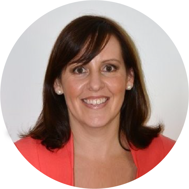 A woman with straight brown hair, wearing a coral blazer and pearl earrings, smiles at the camera against a plain white background—ready to share her journey of overcoming finance blues in a recent Beyond Blue case study.