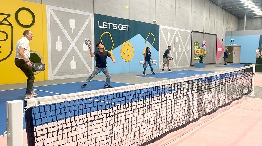 QMetrix team members playing pickleball in a colourful court