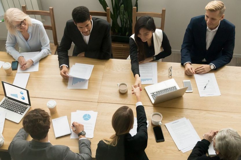 business team meeting with reports and shaking hands