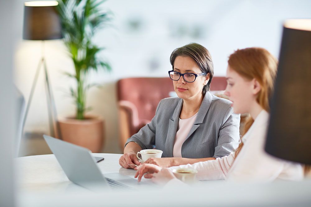 Young women networking in cafe and discussing financial statistics