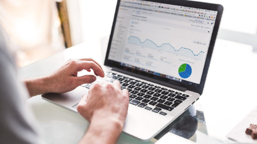 A person using a laptop displaying analytics graphs and charts on the screen, sitting at a glass table—demonstrating the benefits of fast FP&A implementation for real-time financial insights.